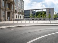 a street scene, with a fence along the road and building in the background in this image,