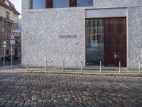 there is an image of street sign on the brick sidewalk in front of building with two signs