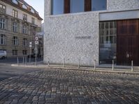 there is an image of street sign on the brick sidewalk in front of building with two signs