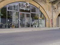 a street with two buildings and graffiti on the walls with old doors and windows that are leaning against each other