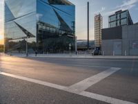 a car is parked at an intersection next to a tall glass building with a sky background