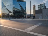 a car is parked at an intersection next to a tall glass building with a sky background