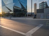 a car is parked at an intersection next to a tall glass building with a sky background