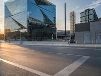 a car is parked at an intersection next to a tall glass building with a sky background