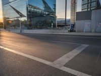 a car is parked at an intersection next to a tall glass building with a sky background