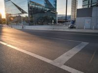 a car is parked at an intersection next to a tall glass building with a sky background