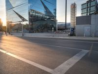 a car is parked at an intersection next to a tall glass building with a sky background