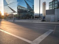 a car is parked at an intersection next to a tall glass building with a sky background