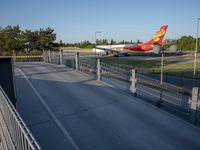a long red and orange airplane on a tarmac next to a fence and trees