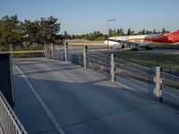 a long red and orange airplane on a tarmac next to a fence and trees