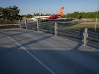 a long red and orange airplane on a tarmac next to a fence and trees