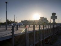 the sun is going behind the control tower at an airport while it sets off from the runway