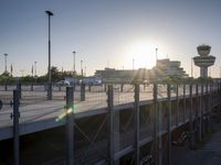 the sun is going behind the control tower at an airport while it sets off from the runway