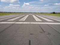 an airport with white markings on the runway and clouds in the background for visual display