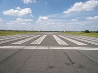 an airport with white markings on the runway and clouds in the background for visual display