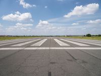 an airport with white markings on the runway and clouds in the background for visual display