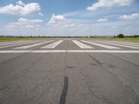 an airport with white markings on the runway and clouds in the background for visual display