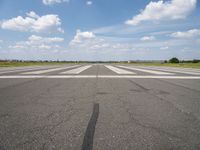 an airport with white markings on the runway and clouds in the background for visual display