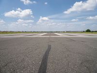 an airport with white markings on the runway and clouds in the background for visual display