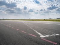 an airport runway with white clouds and a blue sky background that appears to be about 15 degrees empty