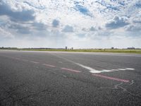 an airport runway with white clouds and a blue sky background that appears to be about 15 degrees empty