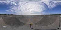 a fish eye view of an airport runway with the sun shining through clouds as it's coming down