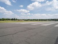 a deserted airport runway with some cars and grass around it at an airfield in summer