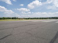 a deserted airport runway with some cars and grass around it at an airfield in summer