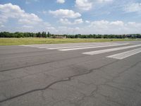 a deserted airport runway with some cars and grass around it at an airfield in summer