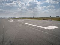 an airport runway with multiple red containers lined up in the middle of it and a cloudy sky