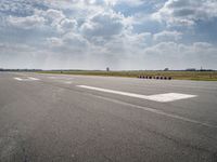 an airport runway with multiple red containers lined up in the middle of it and a cloudy sky