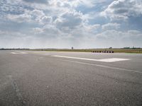 an airport runway with multiple red containers lined up in the middle of it and a cloudy sky