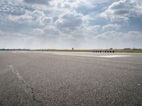 an airport runway with multiple red containers lined up in the middle of it and a cloudy sky