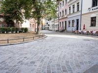 a paved area with a stone paved sidewalk and patio furniture sets on the corner of an intersection