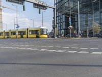 an intersection with the train passing by on the street and people walking by the windows