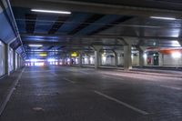 a tunnel with cars parked underneath it at night time and the lighting is turned on