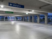 an empty underground parking lot with a green sign and blue street sign on it's sides