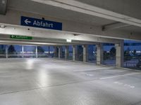 an empty underground parking lot with a green sign and blue street sign on it's sides