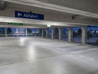 an empty underground parking lot with a green sign and blue street sign on it's sides