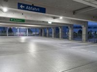 an empty underground parking lot with a green sign and blue street sign on it's sides