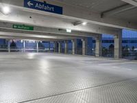 an empty underground parking lot with a green sign and blue street sign on it's sides