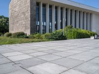 a concrete floor in front of a large building with lots of windows and some bushes