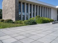 a concrete floor in front of a large building with lots of windows and some bushes