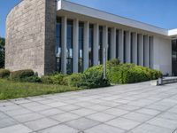 a concrete floor in front of a large building with lots of windows and some bushes