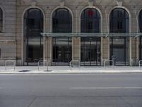 there is a street with cars and pedestrians parked outside of a building in this photo