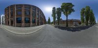 an intersection has a building with lots of trees on it and two cars driving past