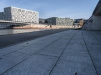 a skateboard sits outside a concrete structure that is next to a street area with a bench