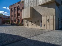 cobblestone driveway surrounded by modern buildings on sunny day with sun reflecting onto the windows