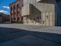 cobblestone driveway surrounded by modern buildings on sunny day with sun reflecting onto the windows