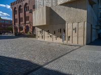 cobblestone driveway surrounded by modern buildings on sunny day with sun reflecting onto the windows